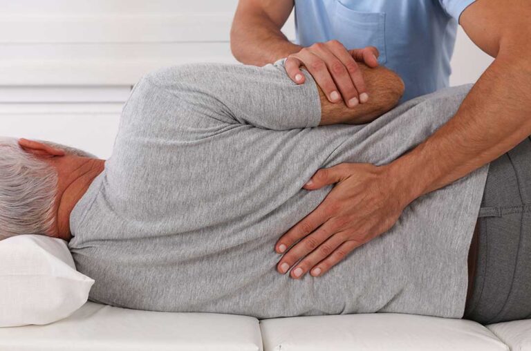 Person using a cold pack on a mildly sore lower back after a chiropractic adjustment.